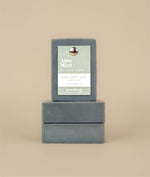 Two aloe mint soaps stacked on their sides with a aloe mint soap sitting on top with a recycled paper tag and metal push pin 