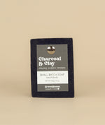 Charcoal and clay soap with a recycled paper tag held in place by a metal push pin 