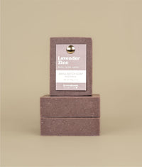 Two horizontally stacked lavender zinc soaps with a vertically stacked lavender zinc soap on top with a recycled paper purple tag held to the soap by a metal push pin 
