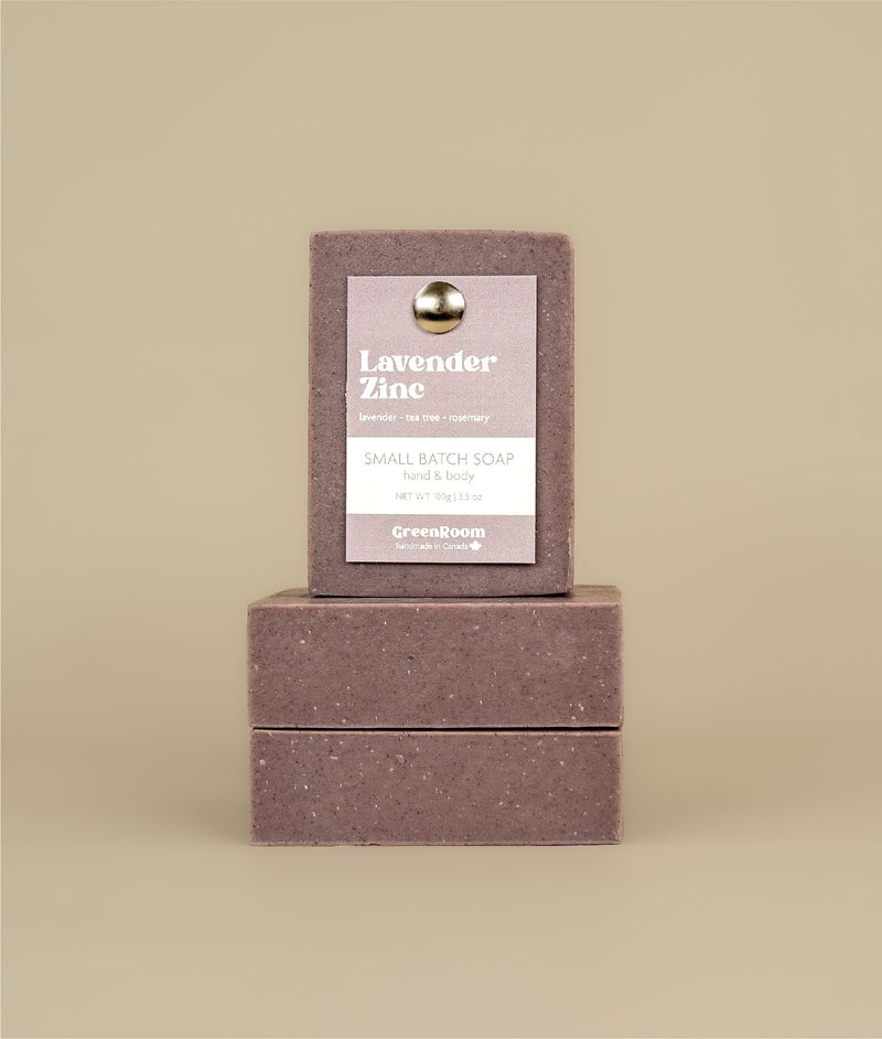 Two horizontally stacked lavender zinc soaps with a vertically stacked lavender zinc soap on top with a recycled paper purple tag held to the soap by a metal push pin 