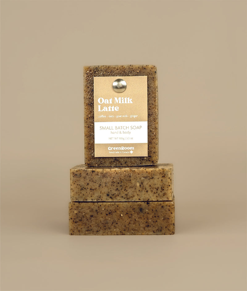 Two horizontal oat milk latte soaps stacked together with a certainly stacked oat milk latte soap with a recycled paper brown and white tag being held up by a metal push pin 